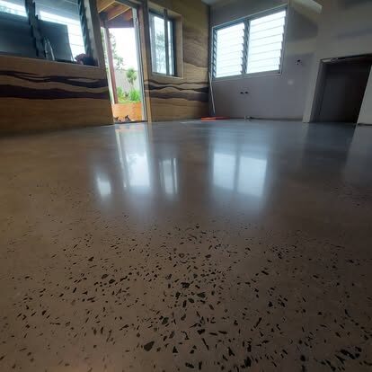 Dark polished concrete floor with a mirror reflection beside a rammed-earth feature wall