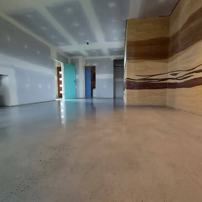 Light polished concrete floor in a new home with a rammed-earth wall